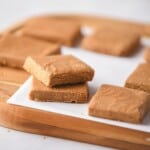 Mexican milk fudge candy cut into squares piled on top of each other on a cutting board.
