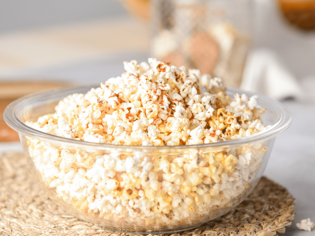 Popcorn topped with seasoning mix in a glass bowl.
