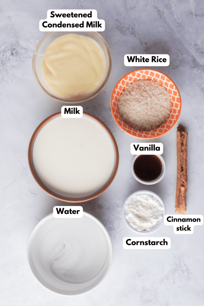 The ingredients needed to make Atole de Arroz labeled and sitting on a white marble surface.