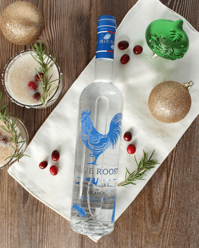 A bottle of Blue Roost Vodka next to the cocktails and Christmas ornaments.