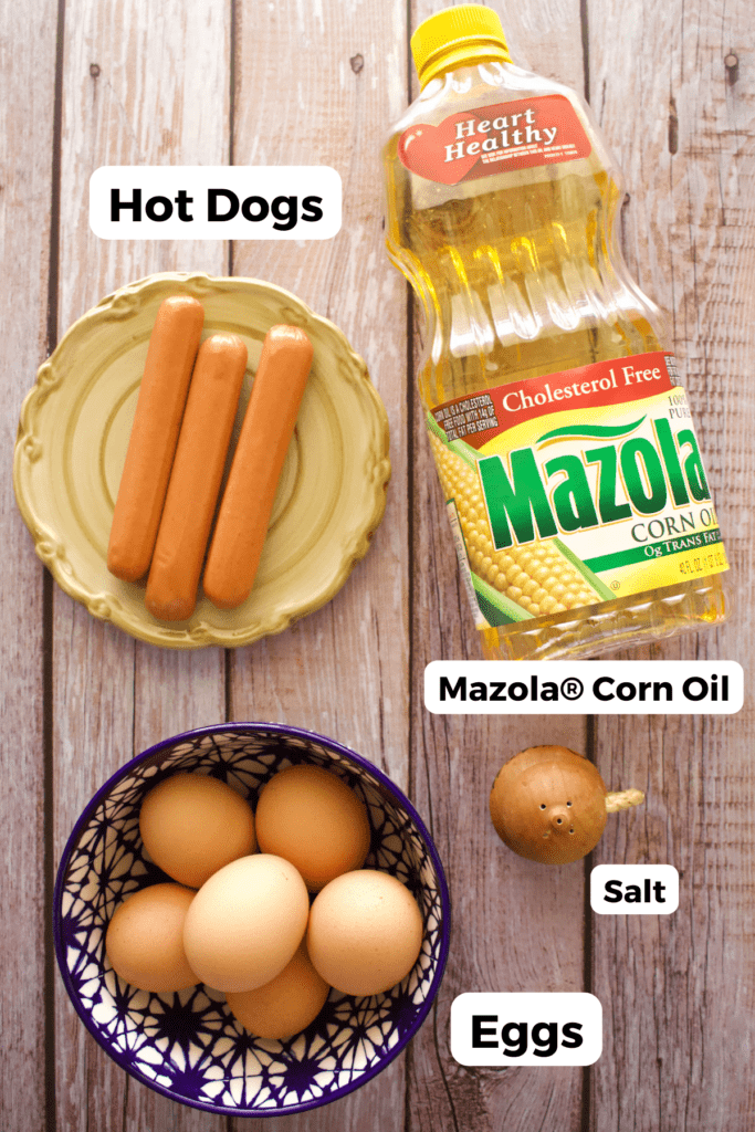 The ingredients needed to make Mexican hot dogs and eggs labeled and sitting on a wooden surface.
