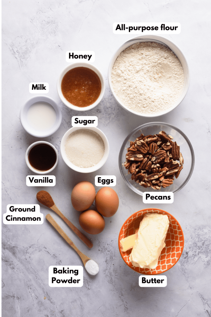 The ingredients needed to make the pecan pound cake labeled and sitting on a white marble surface