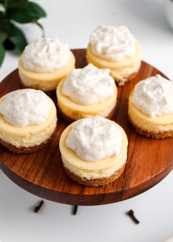 Rompope Cheesecake Bites placed on a round elevated wooded cake stand.