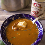 A spoon full of Sopa de Frijol over a bowl of the soup.