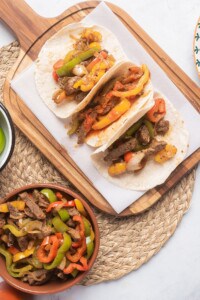 Fajitas de Res Tacos placed on a wooden cutting board.