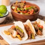 Fajitas de Res Tacos placed on a wooden cutting board.
