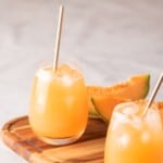 Two glasses served with cantaloupe agua fresca and ice cubes