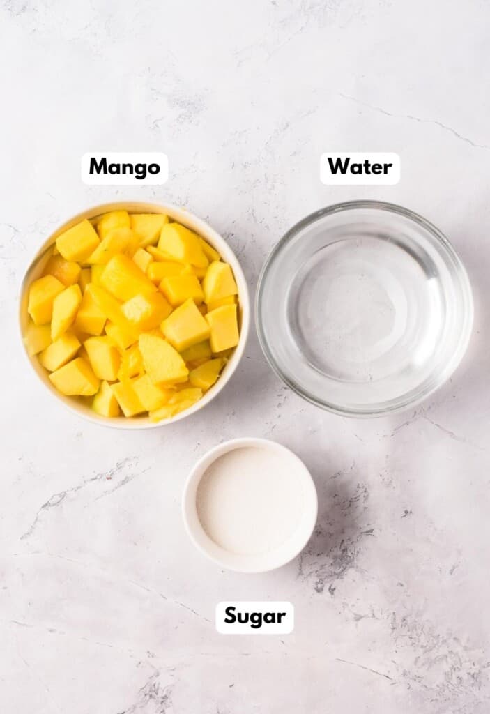 The ingredients needed to make Agua de Mango labeled and sitting on a marble surface.