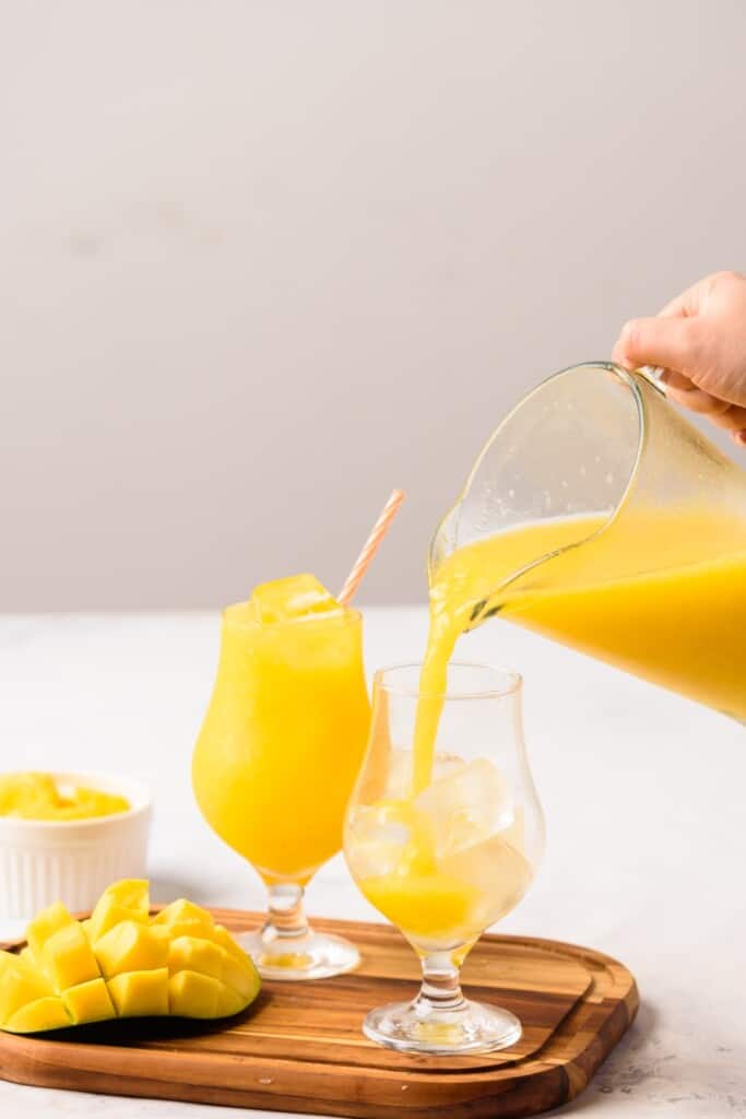 Pouring Agua de Mango into a glass cup with ice.