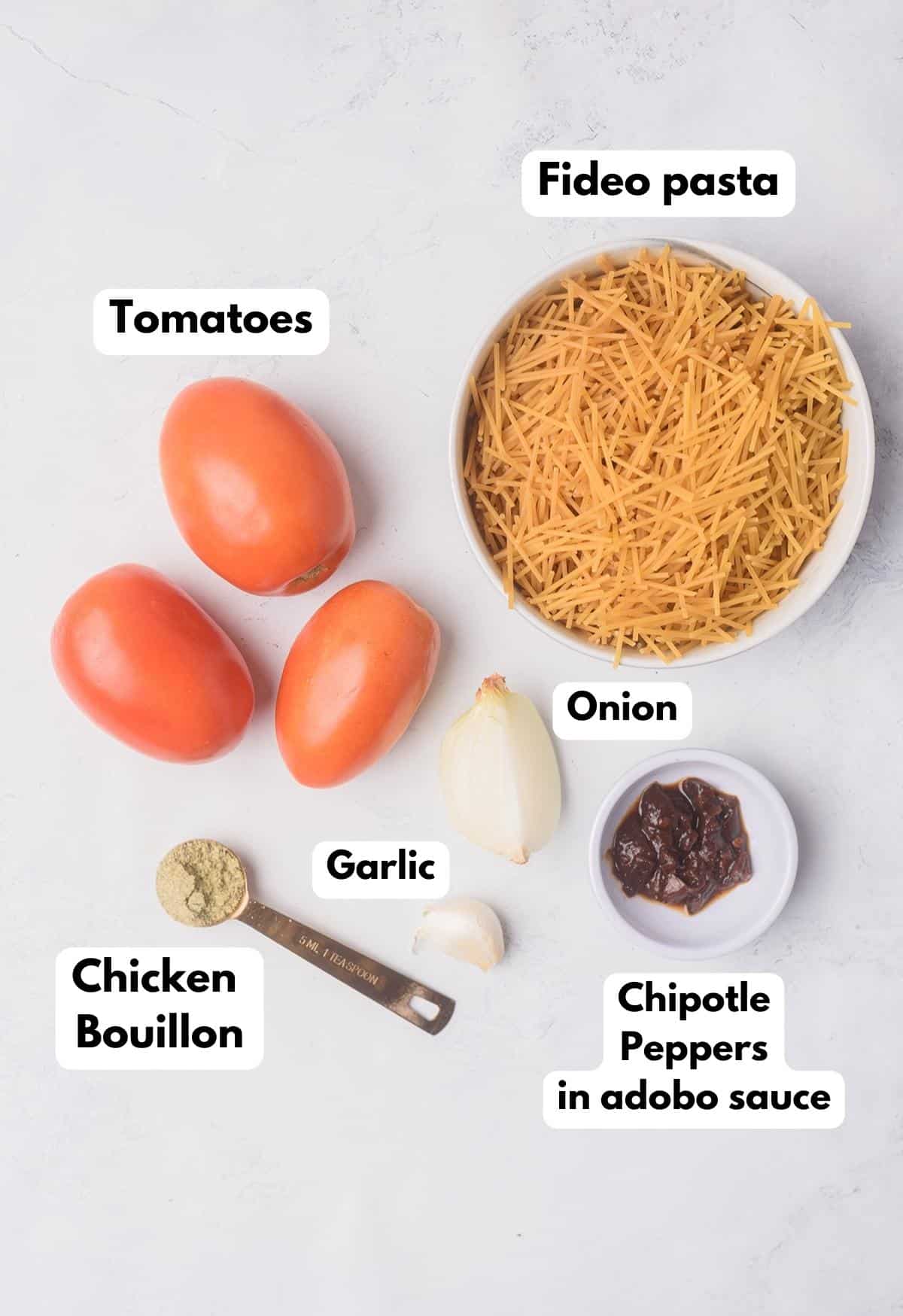 The ingredients needed to make Fideo Seco labeled and sitting on a marble surface.