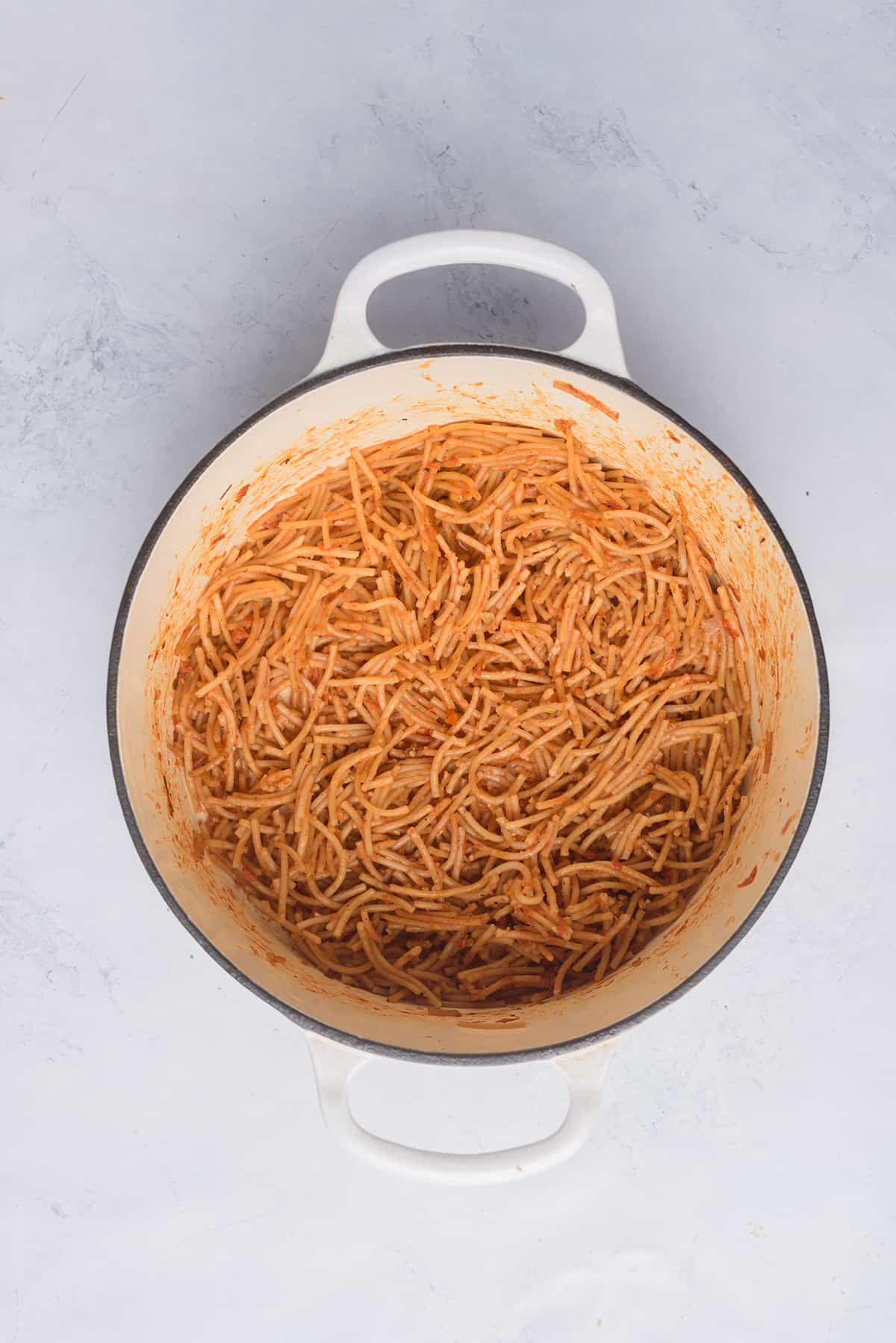 Mexican fideo pasta cooked with tomato sauce in a large stock pot. 