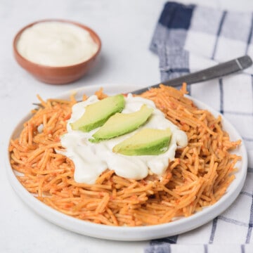 Fideo seco served with Mexican cream and sliced avocado.