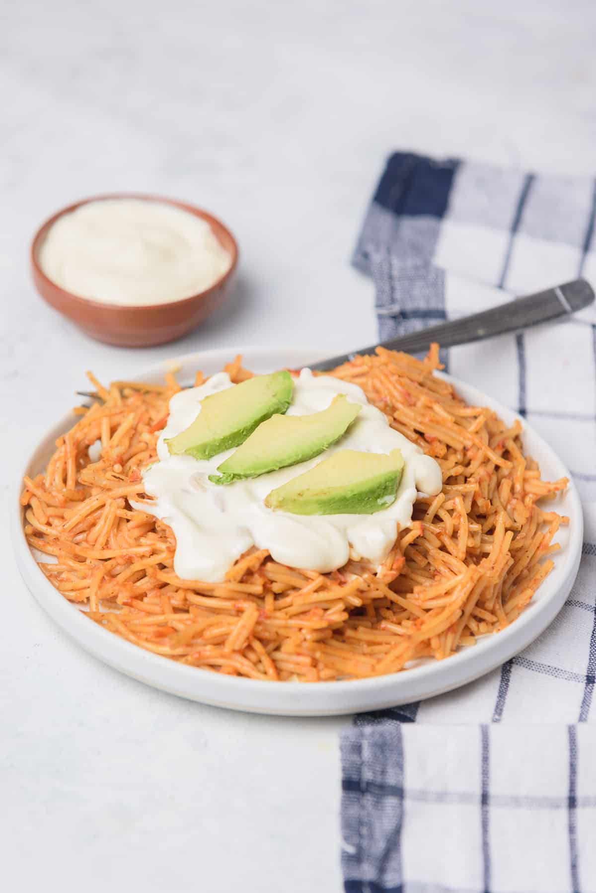 Fideo seco served with Mexican crema and sliced avocado. 