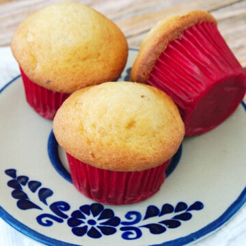 Three Mexican mantecada muffins sitting on a blue plate.