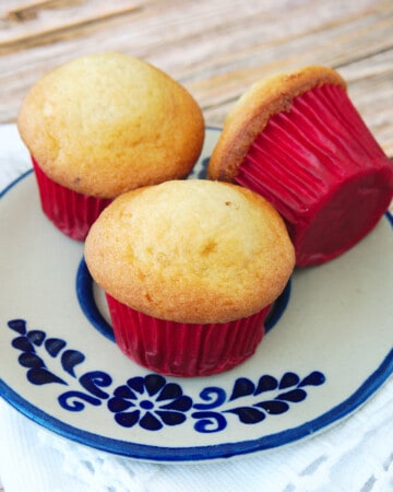 Three Mexican mantecada muffins sitting on a blue plate.