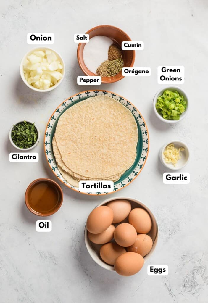 The ingredients needed to make migas labeled and sitting on a marble surface.