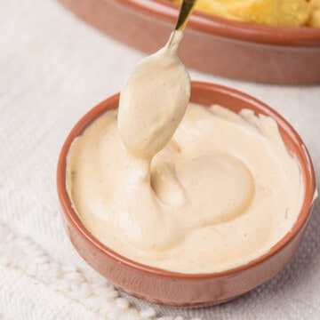 A spoonful dipping into a small bowl of chipotle mayo sauce.