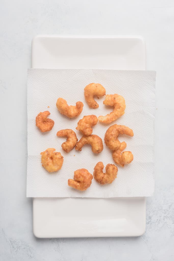 Freshly fried shrimp sitting on a paper towel.