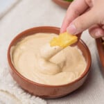A hand dipping a french fry into the chipotle mayo sauce.