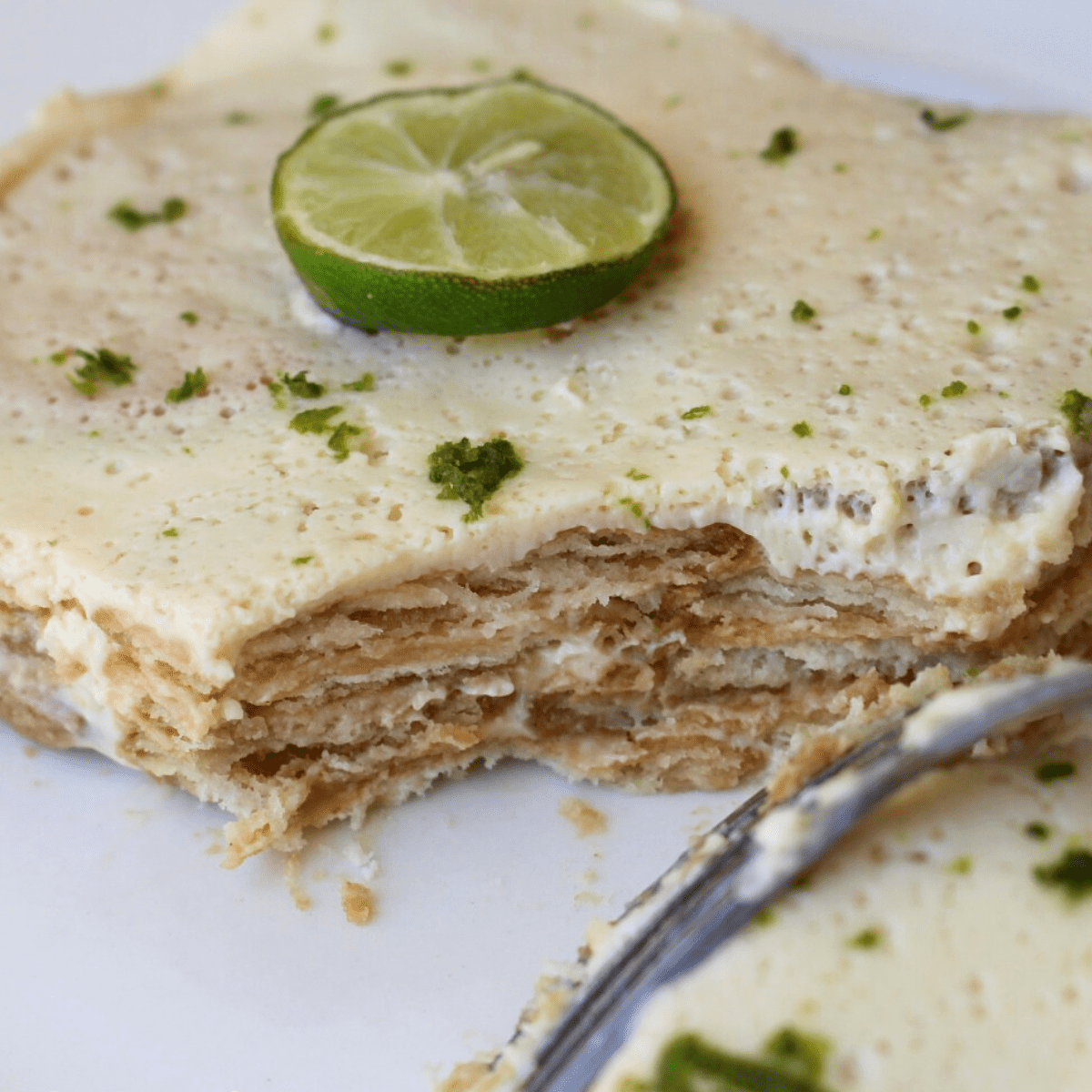 A fork cutting into the lime cake and showing the layers of the dessert.