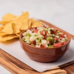 Pineapple pico de gallo served with chips on a wooden cutting board.