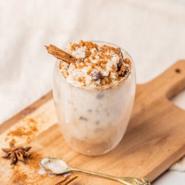 Arroz con leche served in a glass and sitting on a cutting board.
