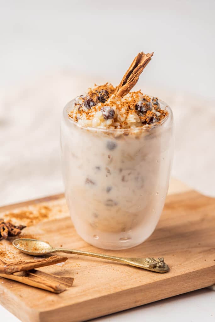 Arroz con leche served in a glass and sitting on a cutting board.