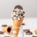 Oreo ice cream served in a cookie cone and standing in a glass jar.