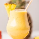 Tropical Mango Pineapple Smoothie served with a fresh slice of fruit.