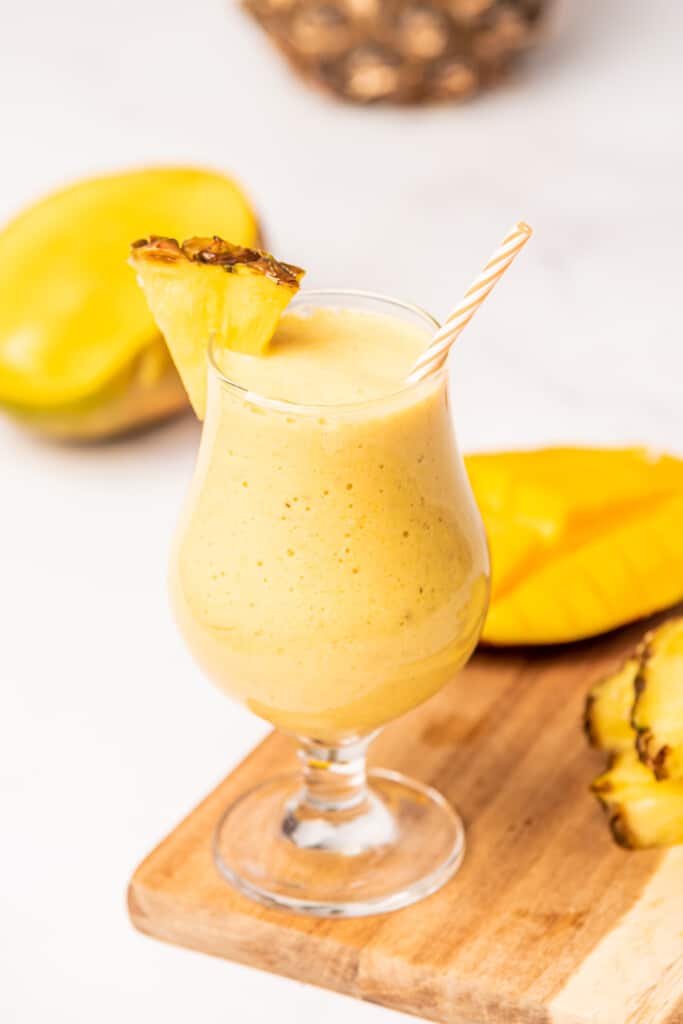 Tropical Mango Pineapple Smoothie served with a straw and a slice of fresh pineapple.