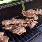 Carne asada cooking on a hot grill.