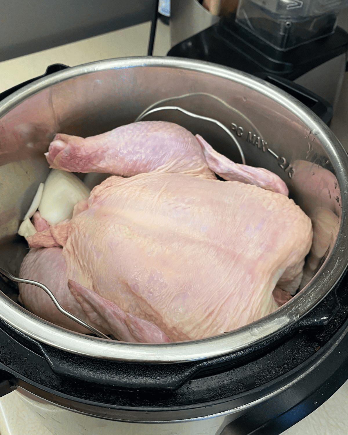 A raw whole chicken sitting in an instant pot.