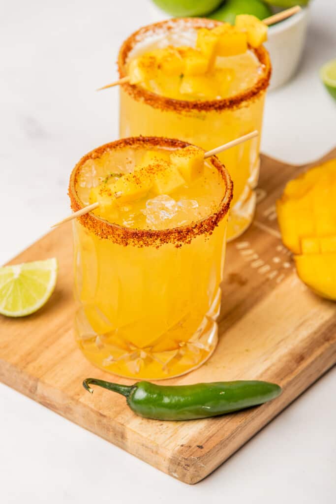 Spicy Mango Margarita served with a skewer of mango pieces.