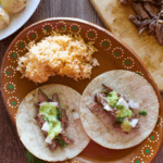 Chipotle Carne Asada served as tacos on a decorative Mexican clay plate next to red rice.