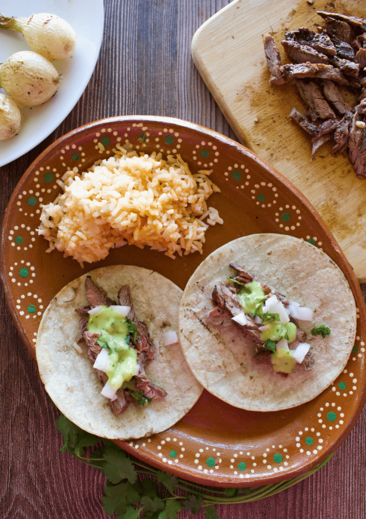 Chipotle Carne Asada served as tacos on a decorative Mexican clay plate next to red rice.