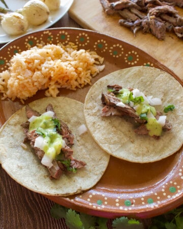 Chipotle carne asada tacos served on a decorative Mexican plate next to red rice.