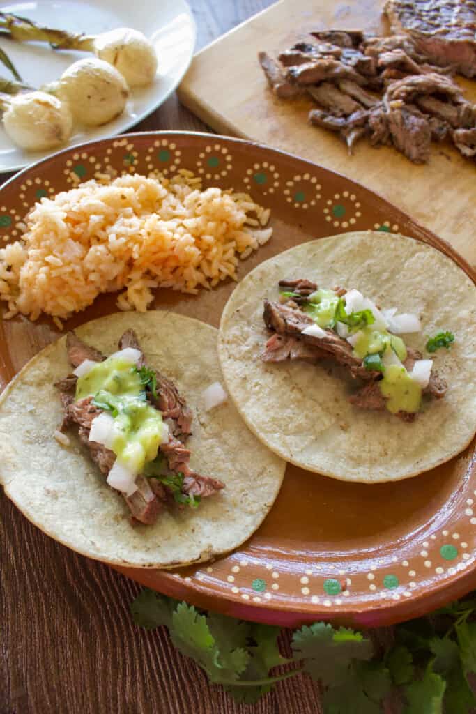Chipotle carne asada tacos served on a decorative Mexican plate next to red rice.