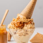 Dulce de leche ice cream served in a glass bowl with a cookie cone on top.
