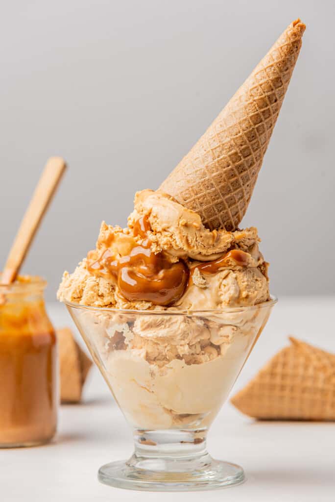 Dulce de leche ice cream served in a glass bowl with a cookie cone on top.