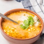 Bowl of Sopa de Elote topped with cheese and Mexican crema.
