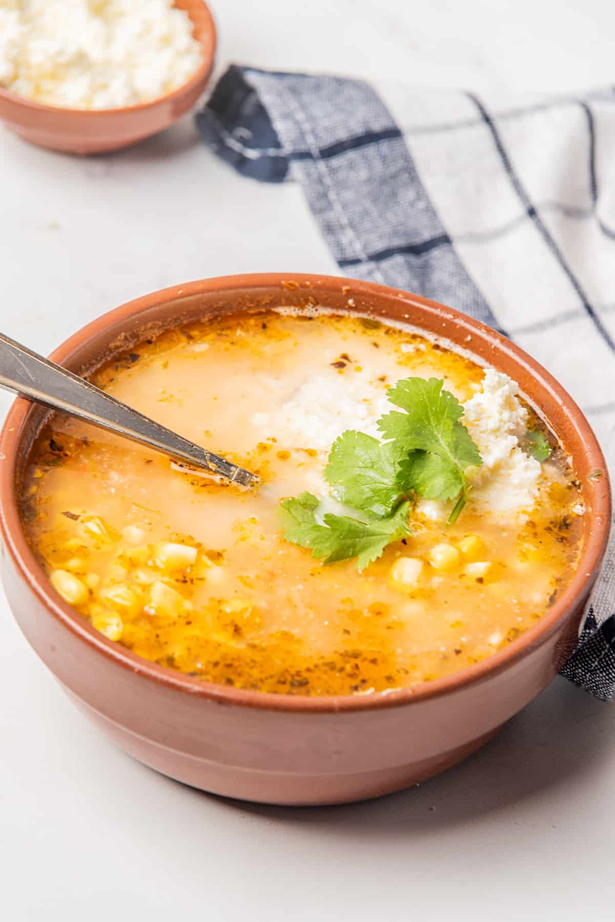 Bowl of Sopa de Elote topped with cheese and Mexican crema.