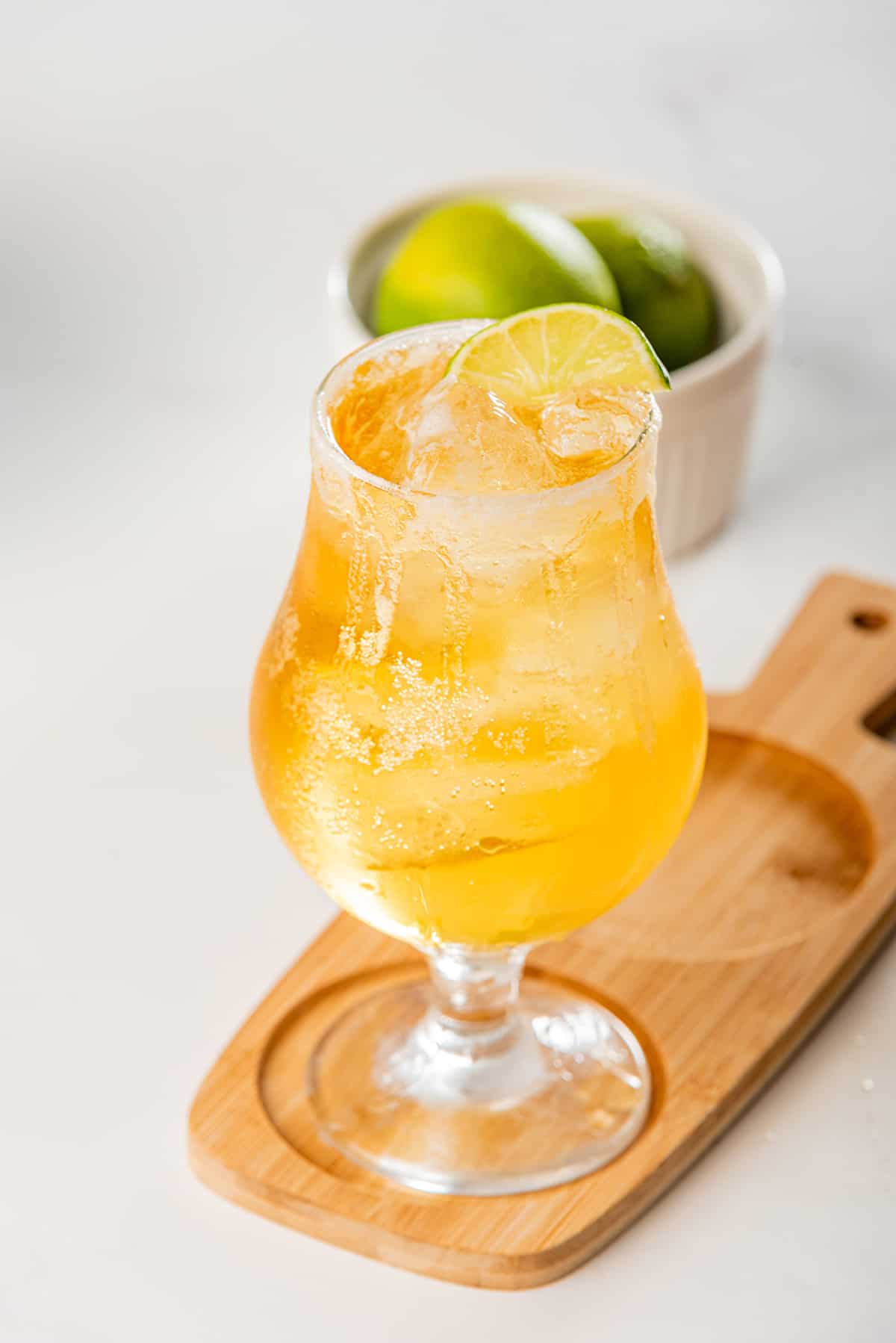 A beer cocktail served in a glass with lime wedges.