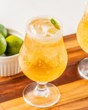 A chelada served in a glass with a lime wedge.