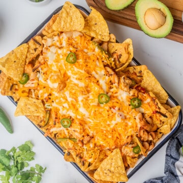 Chicken Fajita Nachos served in a baking dish and topped with jalapeno slices.