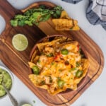 Chicken Fajita Nachos served in a bowl and surrounded by lime and guacamole.