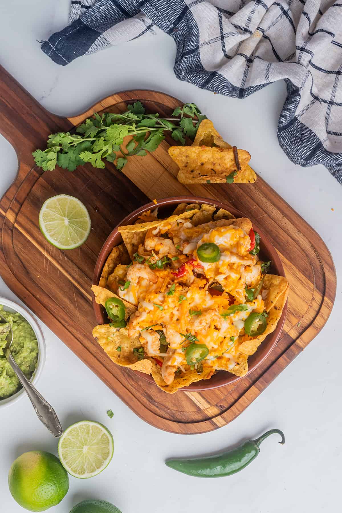 Chicken Fajita Nachos served in a bowl and surrounded by lime and guacamole.