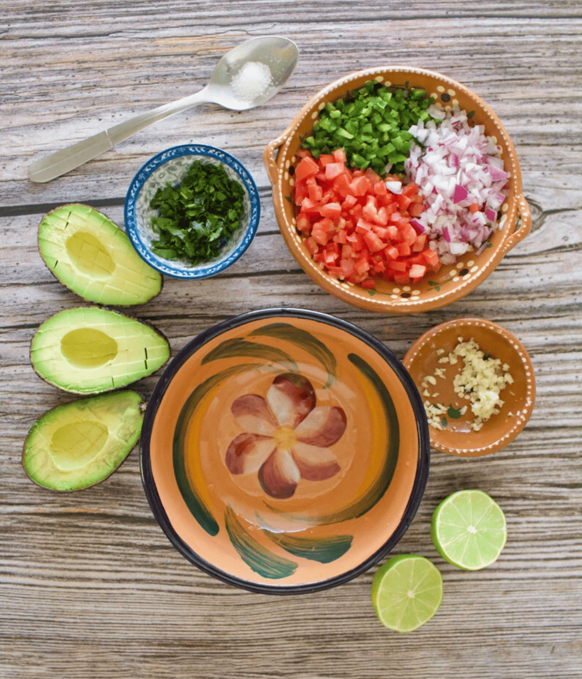 The ingredients needed to make the avocado pico de gallo on a wooden surface.