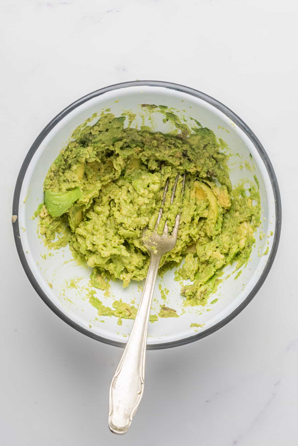Mashing avocado with a fork in a bowl.