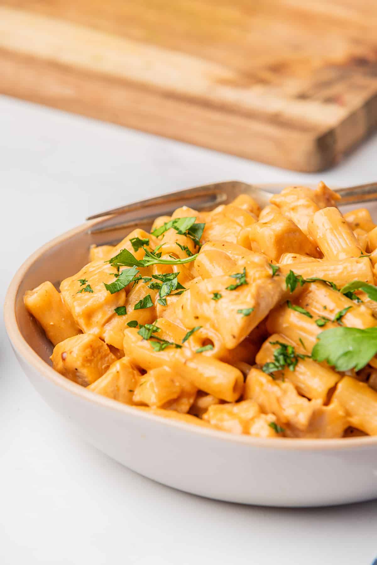 A bowl of spicy chicken chipotle pasta topped with chopped parsley.