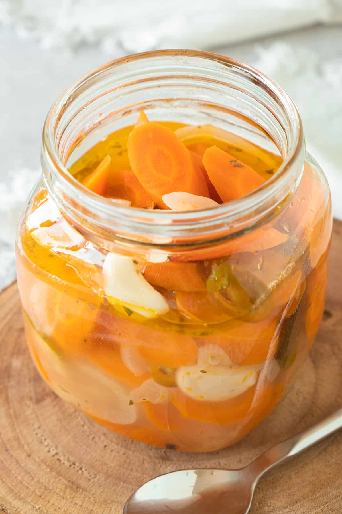 Mexican Pickled Carrots in a glass jar next to a spoon.